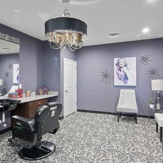 A modern salon interior featuring a hair styling station, purple walls, and a stylish chandelier.