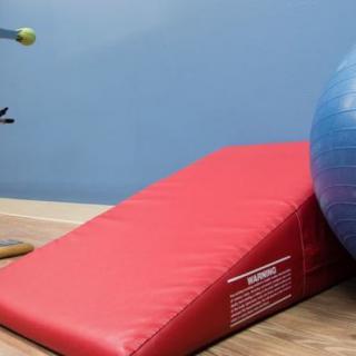 A gym setup featuring a red wedge mat and a blue exercise ball.