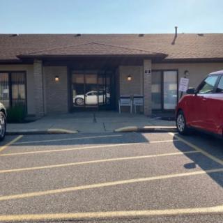 A view of a building entrance with cars parked in front.