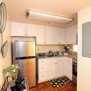 A compact kitchen with white cabinets and stainless steel appliances.