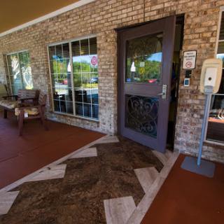 A welcoming entrance featuring a door, brick walls, and a comfortable bench.
