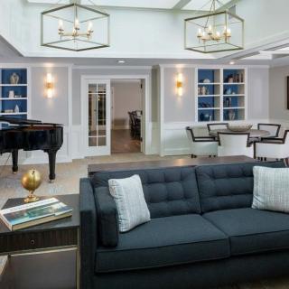 A modern living room featuring a sleek sofa, grand piano, and stylish chandeliers in an open-plan design.