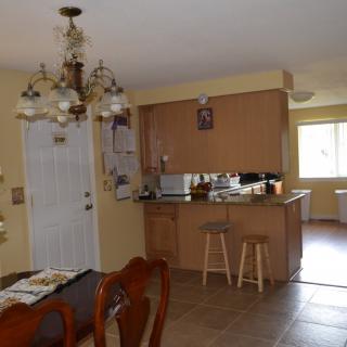 A cozy kitchen and dining area featuring wooden cabinets, a chandelier, and bar stools.