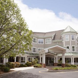 A three-story residential building with a covered entrance and surrounding greenery.