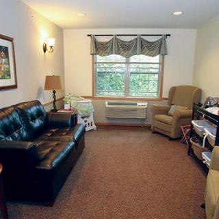 A cozy living room with a sofa, armchair, and window with curtains.