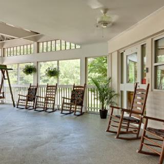A serene outdoor porch featuring rocking chairs, perfect for relaxing in nature.