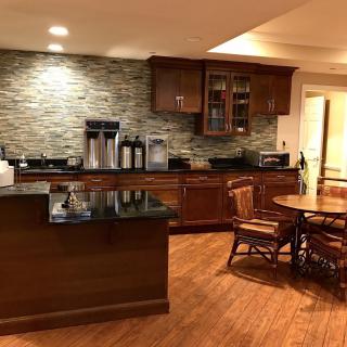 A cozy kitchen area featuring wood cabinets and a stone backsplash, complete with a dining table and modern lighting.