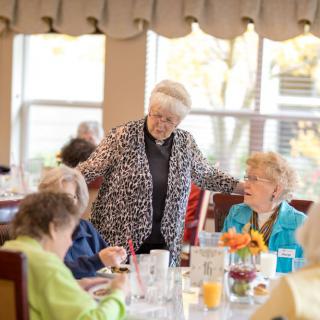 A group of elderly individuals enjoying a meal and conversation in a communal dining area.