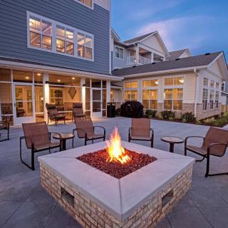 Cozy outdoor fire pit with seating at dusk in front of a modern building.