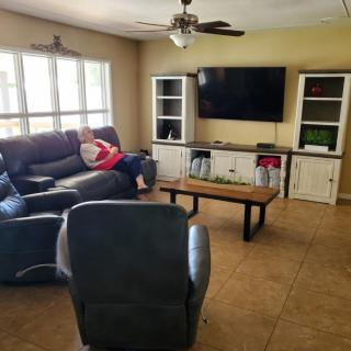 A cozy living room with a sofa, television, and a coffee table. A person is lounging on the sofa.