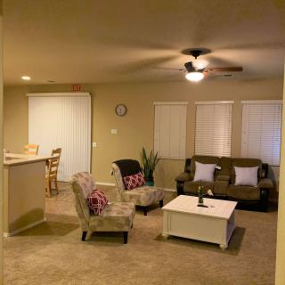 A cozy living room with a sofa, armchairs, and a coffee table under a ceiling fan.