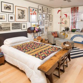 A cozy bedroom featuring an eclectic gallery wall, colorful quilt, and wooden furniture.