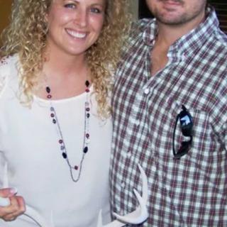 A smiling couple posing together indoors, wearing casual clothing.