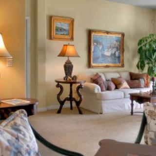 A cozy living room with elegant decor, featuring a sofa, lamps, artwork, and an indoor plant.