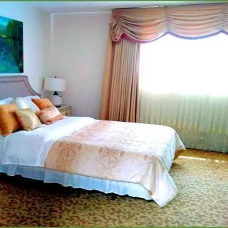 A cozy bedroom with a neatly made bed, soft lighting, and elegant curtains.