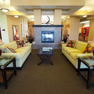 A modern living room with a central fireplace, surrounded by sofas and accent lighting.