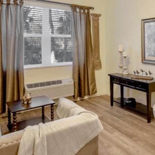 A cozy living room with neutral tones, featuring a comfortable sofa, wooden coffee table, and elegant curtains.