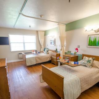 A well-lit hospital room with two patient beds and a welcoming atmosphere.