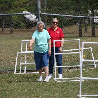 Two people walking near a fenced area in a park.