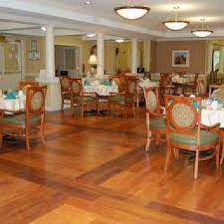 An elegant restaurant dining room with wooden floors and neatly arranged tables and chairs.