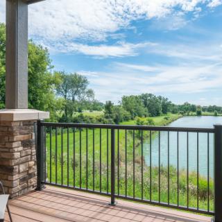A scenic view from a balcony overlooking a lake and greenery.