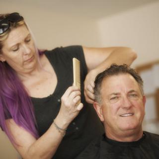 A hairdresser gives a man a haircut at a salon.