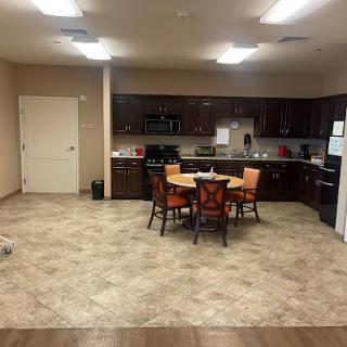 A modern kitchen and dining area featuring a table with orange chairs and contemporary appliances.