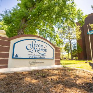 Entrance sign for Seton Manor surrounded by trees and greenery.