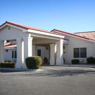 A commercial building with an entrance and parking area under a clear blue sky.