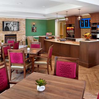 A cozy cafe interior featuring wooden dining tables and chairs, complete with a bar counter and vibrant decor.
