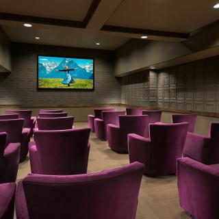 A cozy home theater with purple chairs and a large screen.