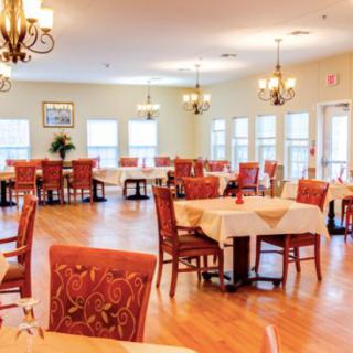 A spacious and elegantly decorated dining room with multiple tables and chandeliers.
