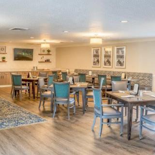 A well-lit dining room with neatly arranged tables and chairs, featuring a wooden floor and elegant decor.