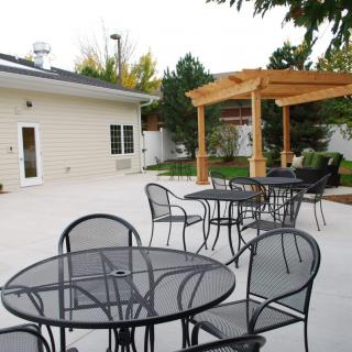 A spacious outdoor patio features metal tables and chairs alongside a wooden pergola.