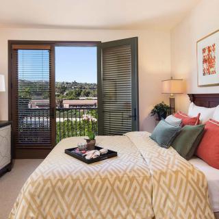 A cozy bedroom with modern decor and a view of the outdoors from a balcony.