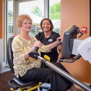 A senior woman engages in a workout session with the guidance of a personal trainer, promoting health and wellness.