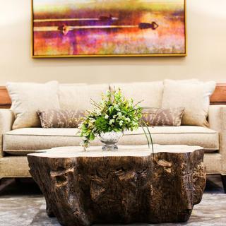 A stylish living room featuring a natural wooden coffee table, a comfortable sofa, and a vibrant piece of abstract artwork on the wall.