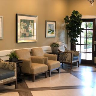 A cozy waiting area featuring comfortable chairs, decorative artwork, and indoor plants.