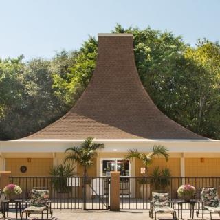 A uniquely designed building with a steep roof and an outdoor patio area surrounded by trees.