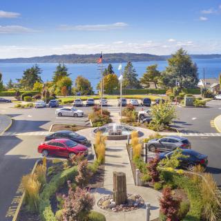 A scenic view of a parking lot overlooking the ocean, surrounded by gardens and trees.