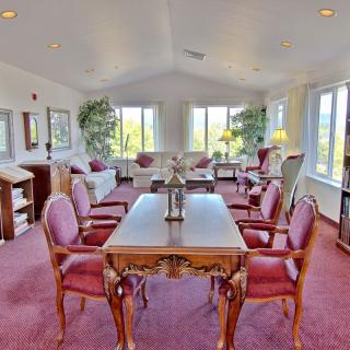 A spacious living room with a dining area, featuring elegant furniture and large windows allowing natural light.