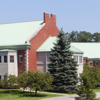 A building with a green roof and brick walls surrounded by trees.