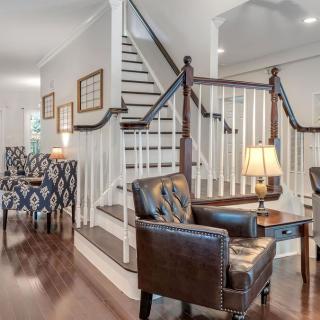 A cozy living room with leather chairs, a side table with a lamp, and a staircase in the background.