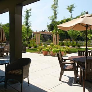 A serene outdoor patio area surrounded by lush greenery and shaded by umbrellas, perfect for relaxation.
