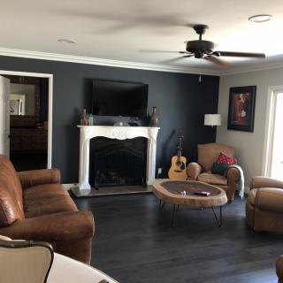 A modern living room featuring a large sofa, fireplace, wall-mounted television, and a guitar in the corner.