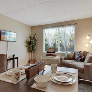 A cozy living room with a dining area, featuring a comfortable sofa, dining table set, and natural light coming through the window.