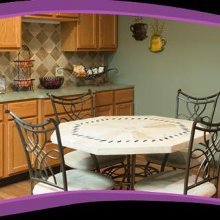 A cozy kitchen with a round dining table and decorative chairs, surrounded by wooden cabinets.