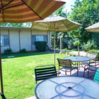 A sunny outdoor patio area with tables, chairs, and umbrellas.