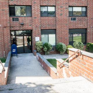 Entrance to a brick apartment building with stairs and sidewalk.