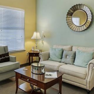 A cozy living room with a sofa, armchair, coffee table, and decorative mirror.